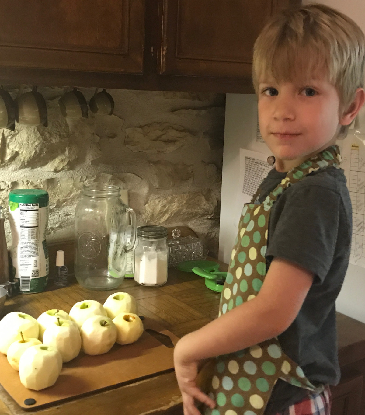Young boy peeling apples looking at camera